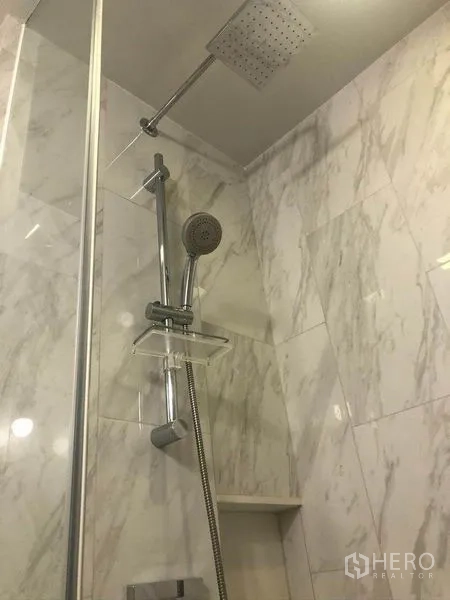 Condominium for sale in Watthana, Bangkok - Modern bathroom with marble tiles and a rain shower with handheld set.