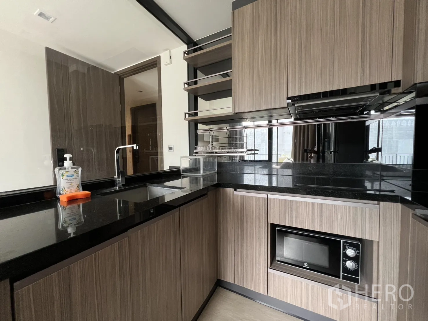 公寓 for rent in Watthana, Bangkok - 厨房黑色石材台面与水槽及木质柜体的近景。
