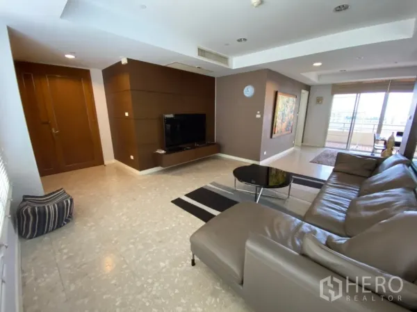 Condominium for rent in Watthana, Bangkok - Living area with TV wall, marble floor and sliding doors opening to the balcony.