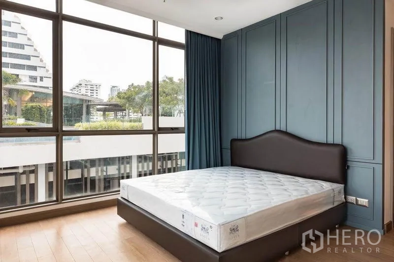 คอนโด ให้เช่าหรือขายในWatthana, Bangkok - ห้องนอนหน้าต่างบานใหญ่ มองเห็นสระและต้นไม้ พร้อมผนังตกแต่งสีน้ำเงิน