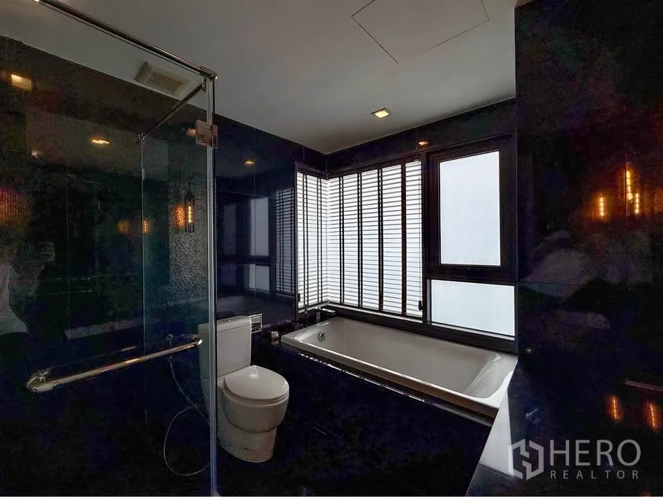 Condominium for rent in Khlong Toei, Bangkok - Bathroom with separate shower and bathtub beside windows with blinds.