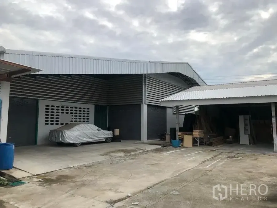 货栈 出租在Mueang Pathum Thani, Pathum Thani - 金属板外墙仓库，设有卷闸门、带顶装卸区与宽阔混凝土院坝，便于卡车通行与停车