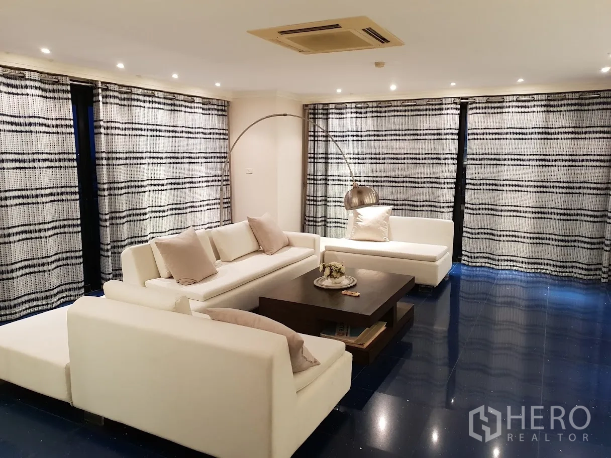 Condominium for rent in Yan Nawa, Bangkok - Cozy second lounge with white sofas, recessed lighting and patterned curtains.