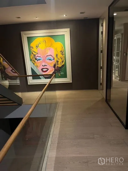 独立式住宅 出租在Wang Thonglang, Bangkok - 楼梯平台，玻璃扶手与色彩鲜艳的波普艺术肖像画。