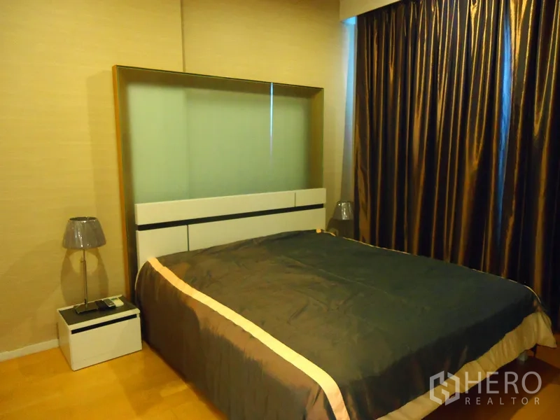 คอนโด ให้เช่าในChatuchak, Bangkok - ห้องนอนอบอุ่น เตียงขนาดใหญ่ โต๊ะข้าง และผ้าม่านกันแสงโทนอุ่น