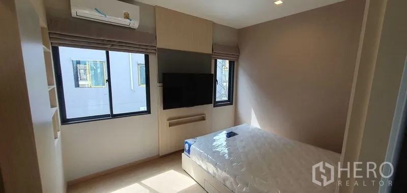 สำนักงานที่บ้าน ให้เช่าในPrawet, Bangkok - ห้องนอนสว่าง เตียงคู่ ทีวีติดผนัง และหน้าต่างมุมห้องพร้อมม่าน