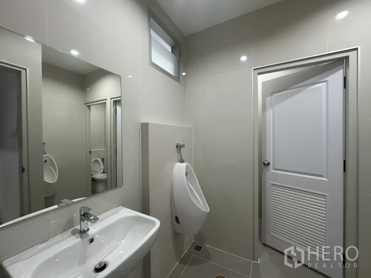 Factory for rent in Bang Phli, Samut Prakan - Clean tiled restroom with sink, urinal and toilet cubicle.