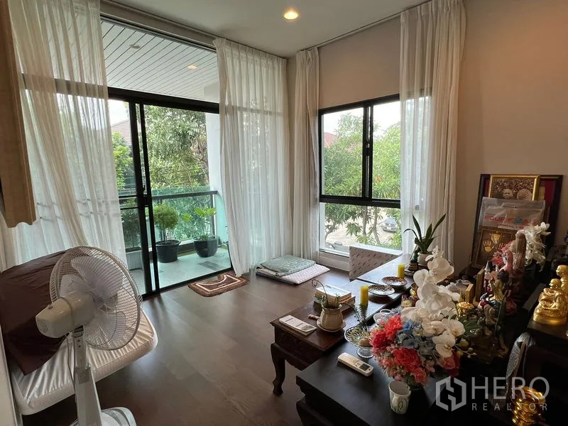 Detached House for sale in Bang Kapi, Bangkok - Bright multi-purpose room with floor-to-ceiling windows and a balcony facing greenery.