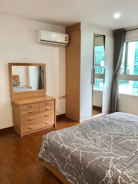 Condominium for rent or sale in Watthana, Bangkok - Bedroom corner with dresser, mirrored wardrobe, window, and wall-mounted air conditioner.