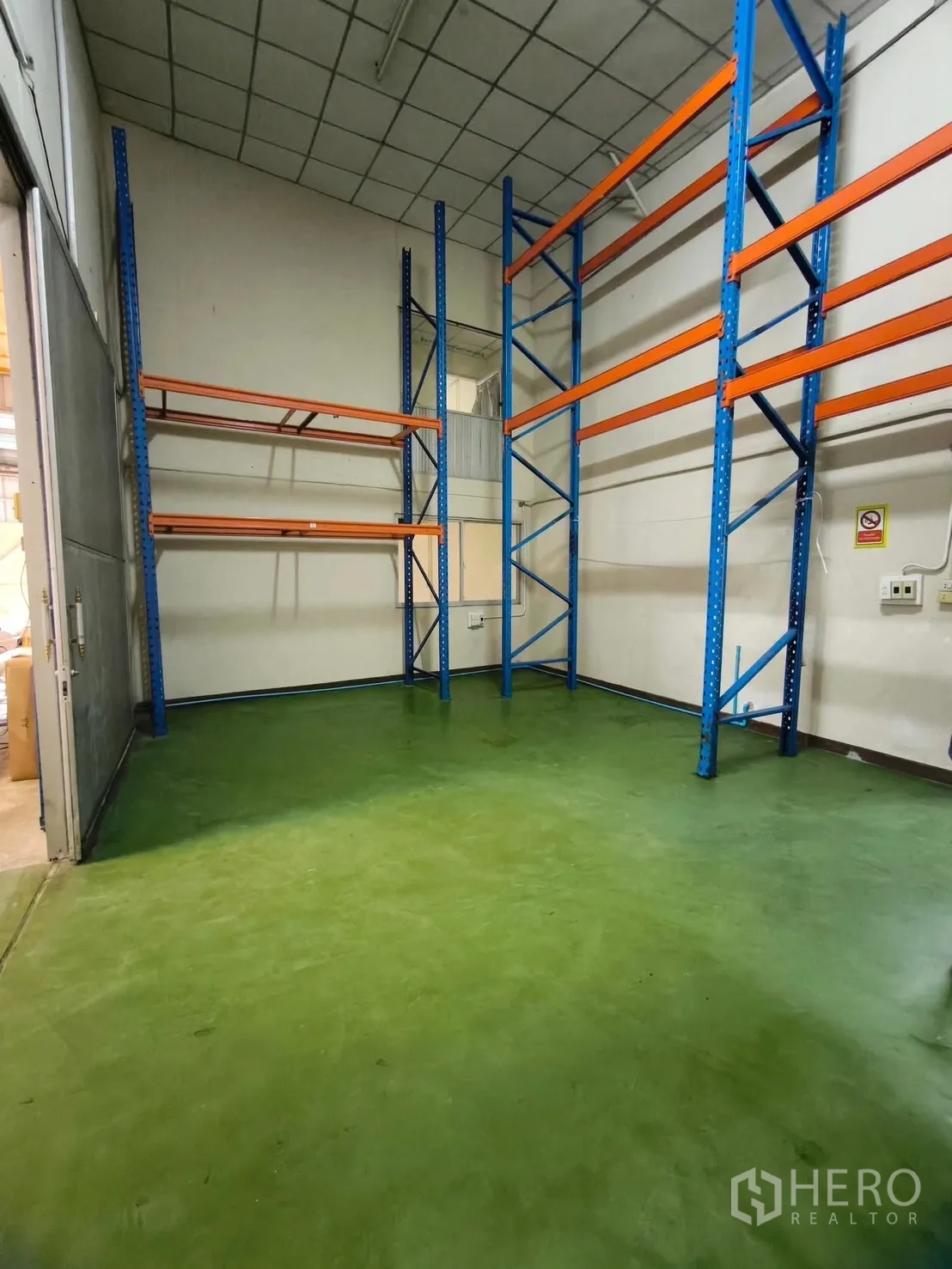 Warehouse for rent in Suan Luang, Bangkok - Tall blue and orange pallet racking in a storage room with green epoxy floor.
