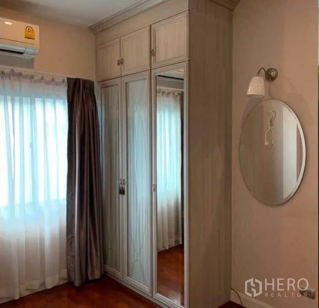 独立式住宅 出售在Mueang Pathum Thani, Pathum Thani - 卧室一角，内置带镜衣柜、柔和窗帘及空调。