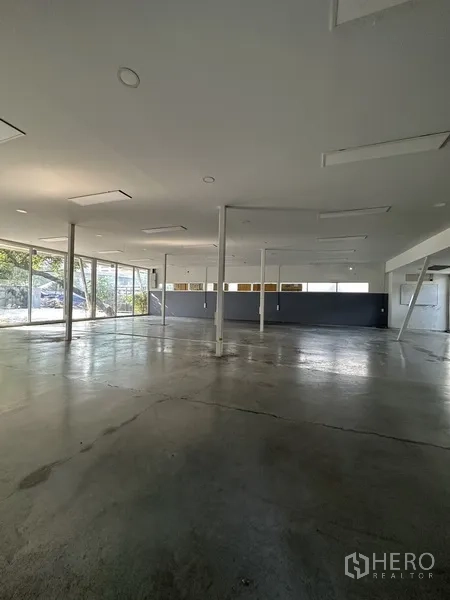 Detached House for rent in Phaya Thai, Bangkok - Open-plan ground floor hall with concrete floor, support columns and floor-to-ceiling windows.