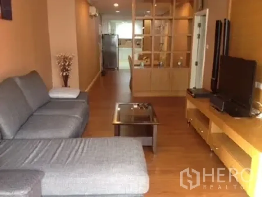 คอนโด ให้เช่าหรือขายในWatthana, Bangkok - ห้องนั่งเล่นโซฟาเข้ามุมสีเทา โต๊ะกลางกระจก และชั้นวางทีวี พื้นไม้