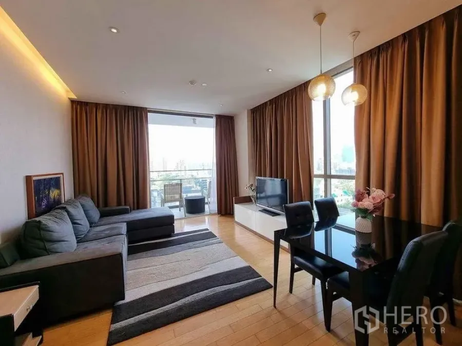 Condominium for rent in Watthana, Bangkok - Spacious living room opening to a balcony with dining set and pendant lights.