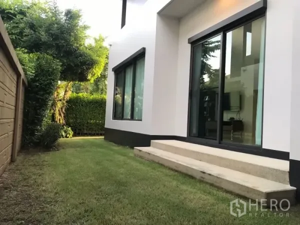 Detached House for rent in Bang Kapi, Bangkok - Private backyard lawn along the house with sliding glass door and privacy hedge.