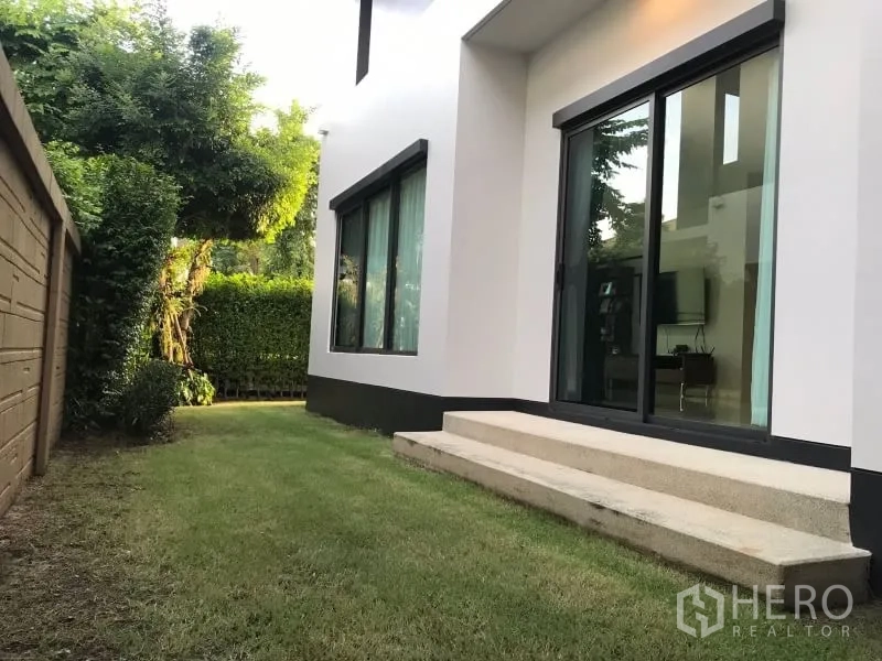 Detached House for rent in Bang Kapi, Bangkok - Private backyard lawn along the house with sliding glass door and privacy hedge.