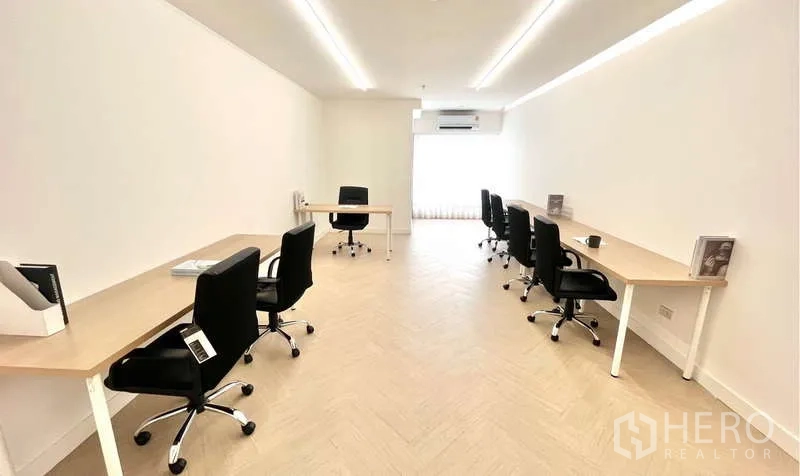 Office Space for rent in Watthana, Bangkok - Long office room with multiple desks, overhead LED lights, and light wood floors.