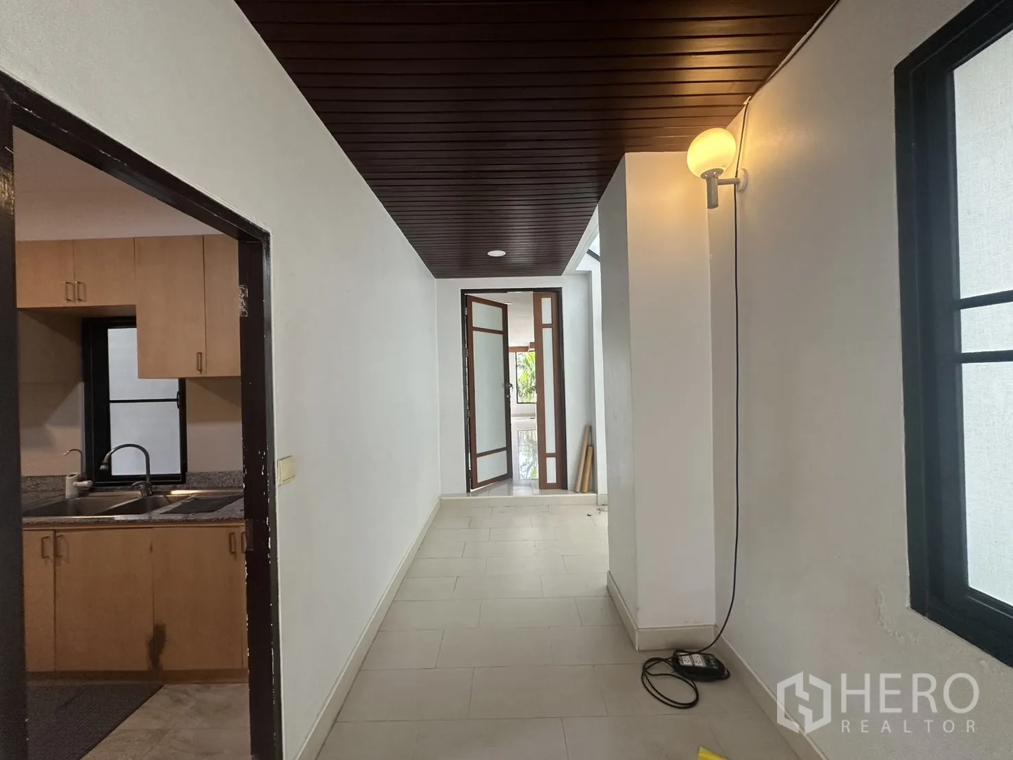独栋房屋 for rent in Watthana, Bangkok - 厨房旁走廊，深色木吊顶，通向玻璃门