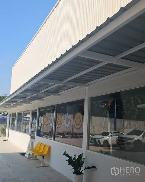 สำนักงาน ให้เช่าในBang Phli, Samut Prakan - ระเบียงทางเดินมีกันสาดโลหะ กระจกเต็มบาน เก้าอี้สีเหลือง และพื้นที่จอดรถ