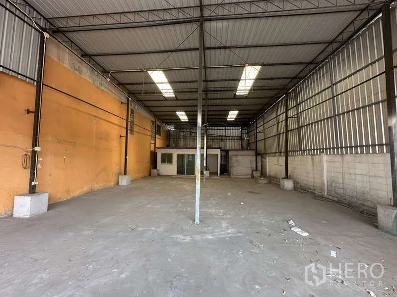 Warehouse for rent in Pak Kret, Nonthaburi - Secondary storage bay with high roof, concrete floor, and rear office rooms.