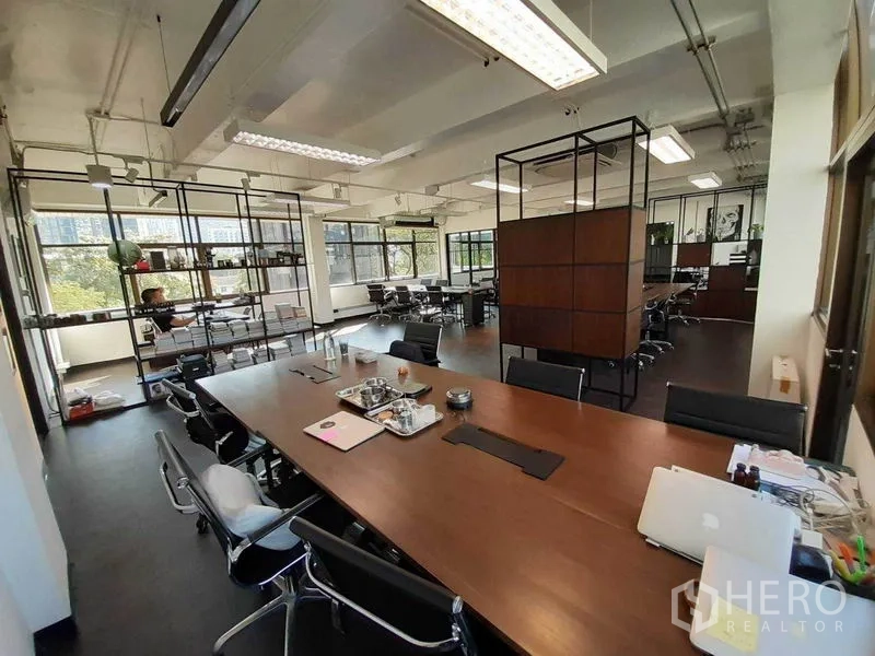 办公空间 出租在Khlong Toei, Bangkok - 带大型会议桌的明亮办公区，天花灯具与开阔窗景绿意可见。