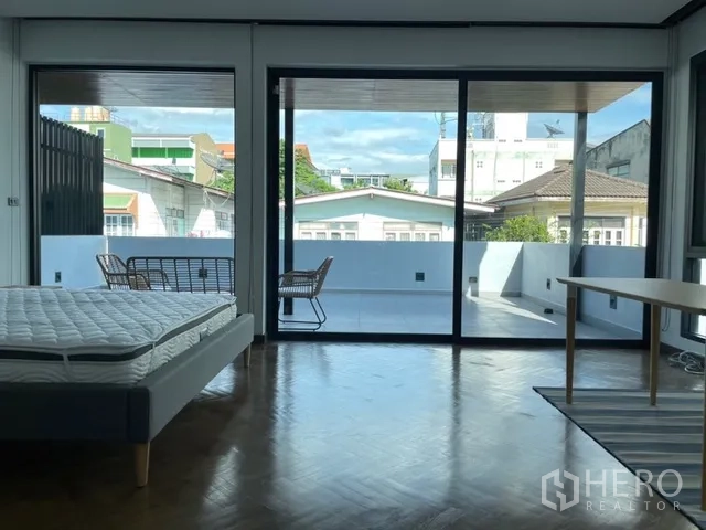 Detached House for rent in Watthana, Bangkok - Bedroom facing a wide balcony through sliding glass doors.