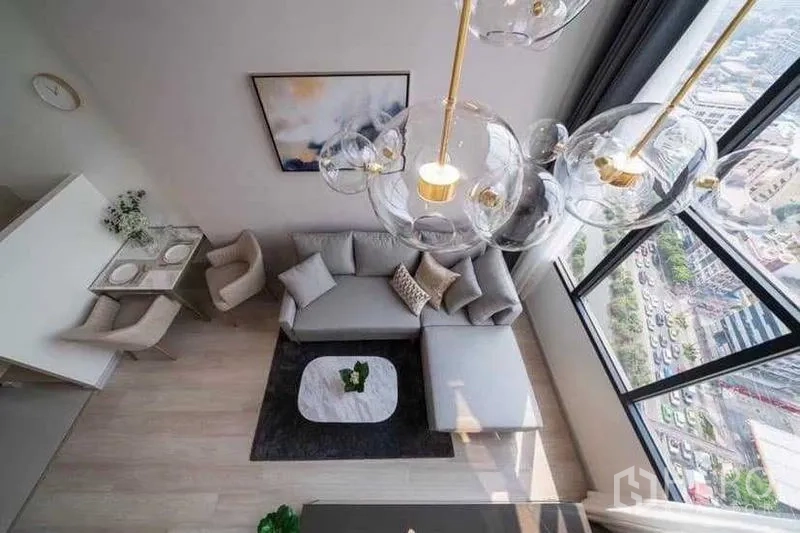 Condominium for rent in Sathon, Bangkok - Aerial view of living space with gray sofa, chandelier and large windows.