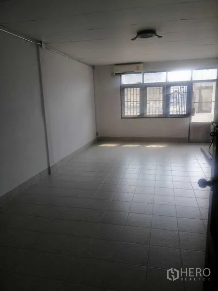Shophouse for rent in Khlong Toei, Bangkok - Large upper room with air conditioner and barred windows.
