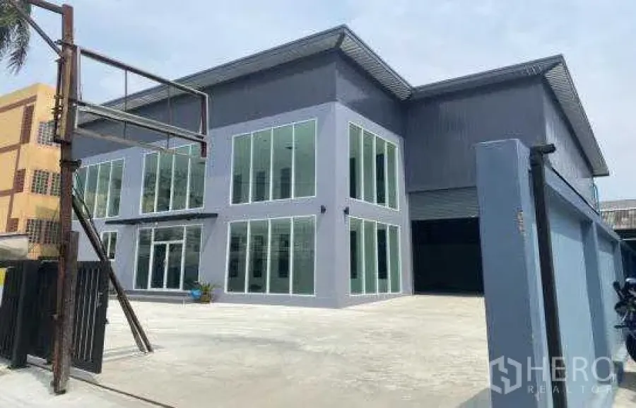 货栈 出租在Prawet, Bangkok - 从大门外看整体现代仓库园区，含两层办公楼、高跨屋顶与宽大停车前场。
