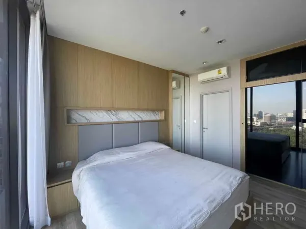 公寓 出租 - 采光充足的卧室，木质床头柜、超大窗户与城市景观。