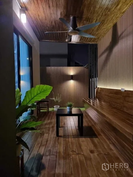 独立式住宅 出售在Khan Na Yao, Bangkok - 带顶木质露台，吊扇、长椅与绿植，夜间灯光温馨。