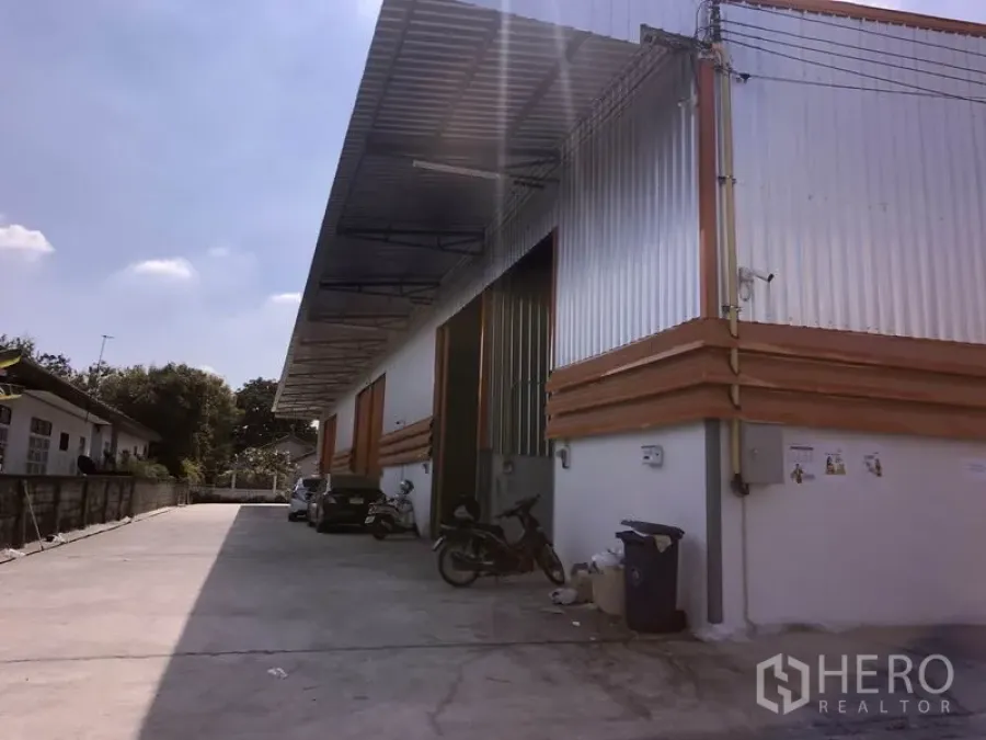 货栈 出租在Lam Luk Ka, Pathum Thani - Lam Luk Ka 区金属板外墙仓库，屋顶挑高，配大型卷门、带遮雨装卸区与宽阔混凝土车道，便于卡车进出
