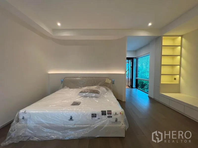 Detached House for sale in Saphan Sung, Bangkok - Master bedroom with soft accent lighting, display shelving and a window to greenery.