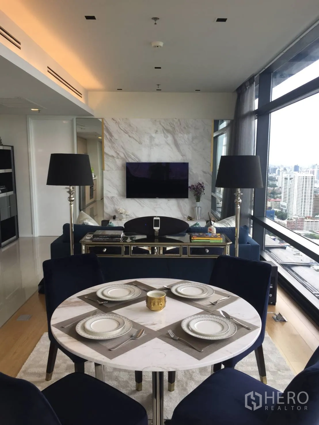 Condominium for rent or sale in Ratchathewi, Bangkok - Cozy dining area facing a marble TV wall and full-height glass with city views.