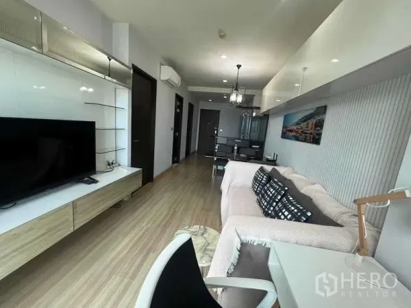 คอนโด ขายในKhlong Toei, Bangkok - พื้นที่นั่งเล่นแบบโอเพ่นพร้อมชั้นวางทีวี ทางเดินยาวสู่โซนทานอาหาร พื้นไม้