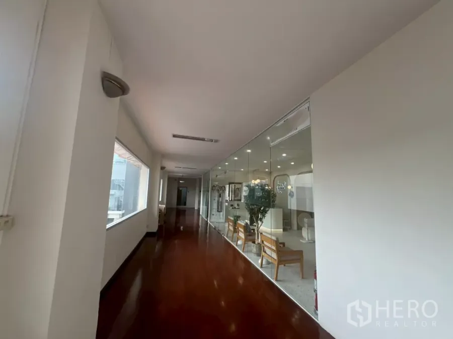 零售空间 出租在Watthana, Bangkok - 明亮走廊，亮面木地板，玻璃隔断的零售单元，室内座椅与顶灯，位于曼谷建筑内