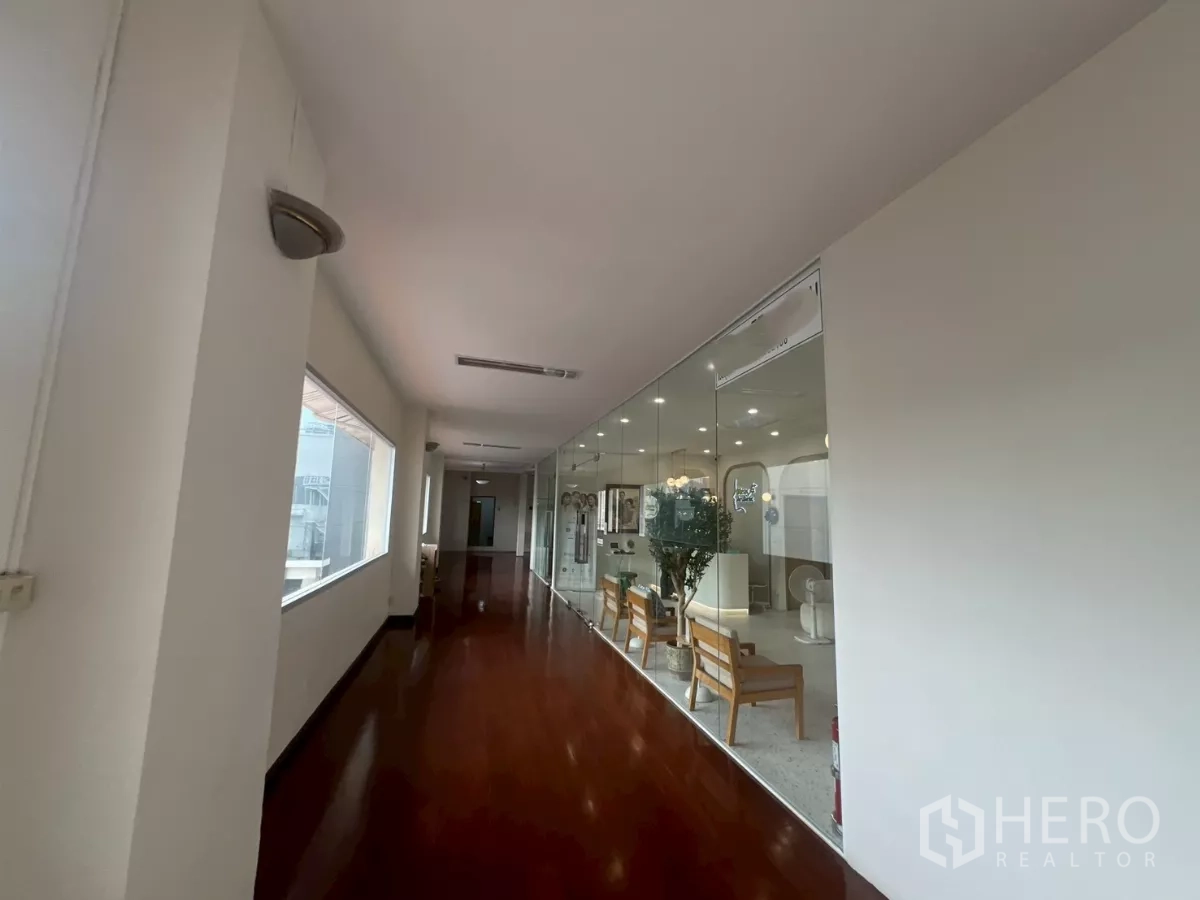 零售空间 出租在Watthana, Bangkok - 明亮走廊，亮面木地板，玻璃隔断的零售单元，室内座椅与顶灯，位于曼谷建筑内