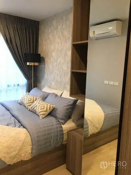 คอนโด ขายในBang Na, Bangkok - ห้องนอนอบอุ่นในคอนโดย่านบางนา เตียงคู่ วอลเปเปอร์ลายสวย โคมไฟ ม่านทึบ และเครื่องปรับอากาศติดผนัง