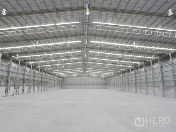 Factory for rent in Bang Pakong, Chachoengsao - High-clearance warehouse interior with steel truss roof and polished concrete floor.