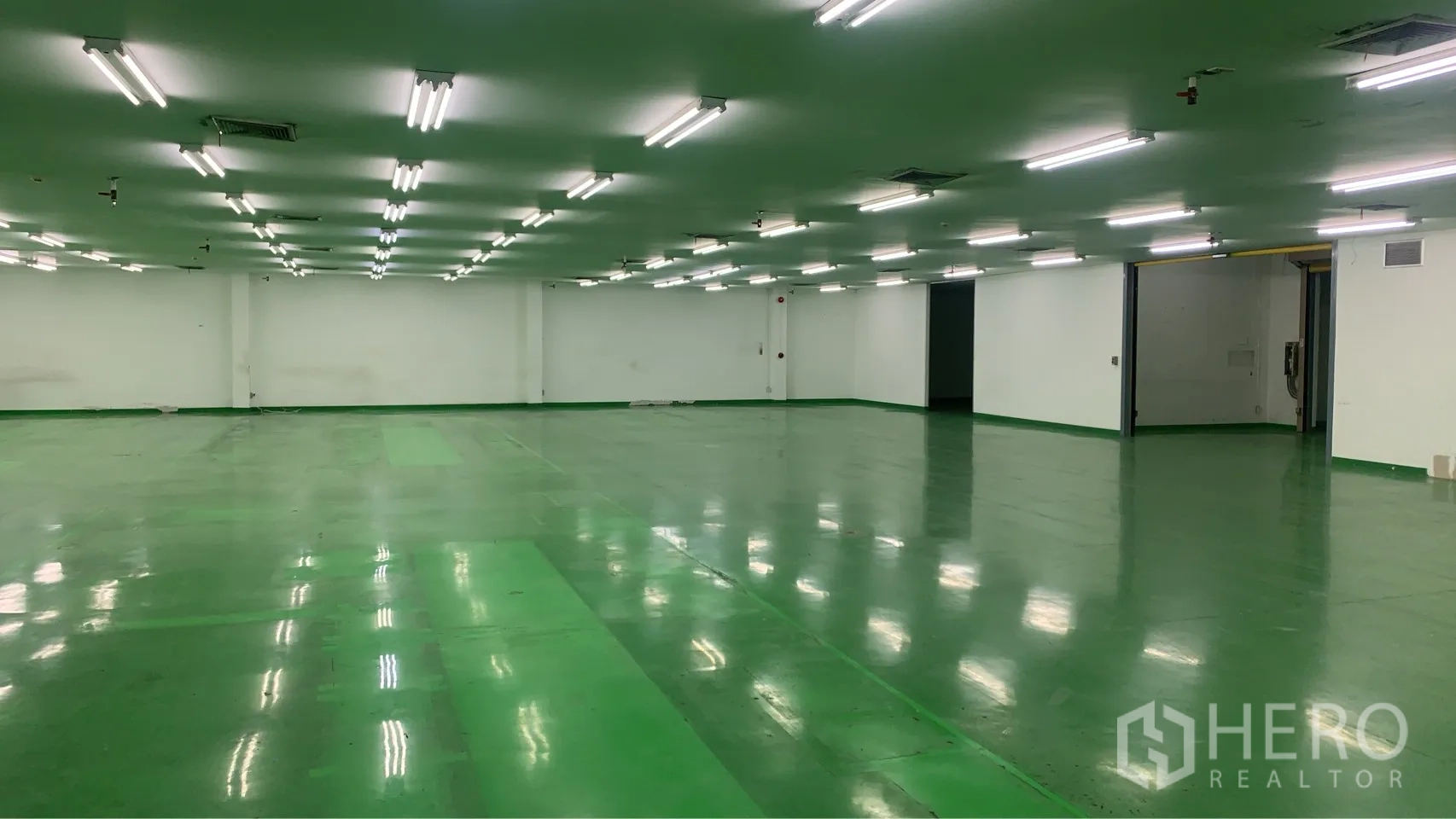Factory for rent in Mueang Samut Prakan, Samut Prakan - Industrial hall with sliding door openings, polished green floor and uniform ceiling lighting.