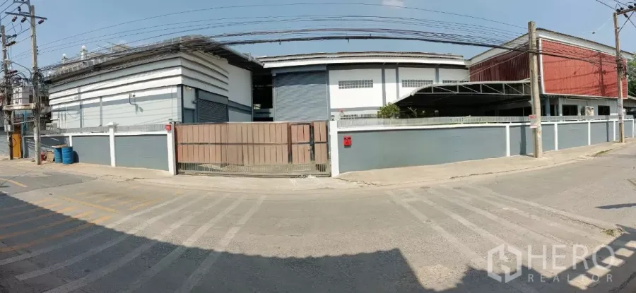 工厂 出租或出售在Bang Khun Thian, Bangkok - 曼谷邦坤天区独栋工厂外观，带大门与围墙，卷门与架空电线的街景。
