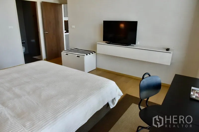 คอนโด ให้เช่าในPhaya Thai, Bangkok - มุมมองห้องนอนไปยังชั้นวางทีวีติดผนังและทางเข้าห้องน้ำในคอนโดทันสมัย.