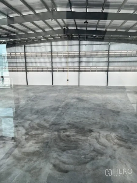 Factory for rent in Bang Sao Thong, Samut Prakan - Spacious warehouse interior with polished concrete floor and steel roof structure.