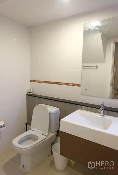 Detached House for rent in Suan Luang, Bangkok - Bright bathroom with white tiles, wall mirror, vanity sink, and toilet.