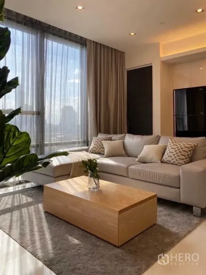 Condominium for rent in Sathon, Bangkok - Alternate angle of the living room showing sofa, wood coffee table and tall windows.