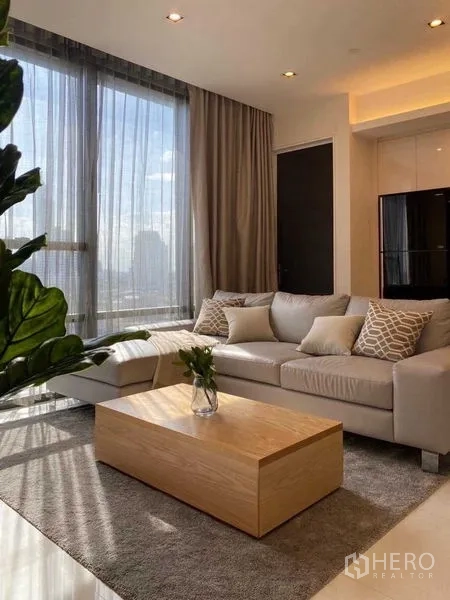 Condominium for rent in Sathon, Bangkok - Alternate angle of the living room showing sofa, wood coffee table and tall windows.