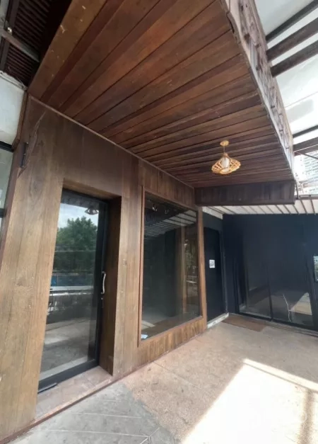 พื้นที่ขายปลีก ให้เช่า - มุมมองด้านหน้าร้านกรุไม้ใต้กันสาดพร้อมโคมไฟห้อย
