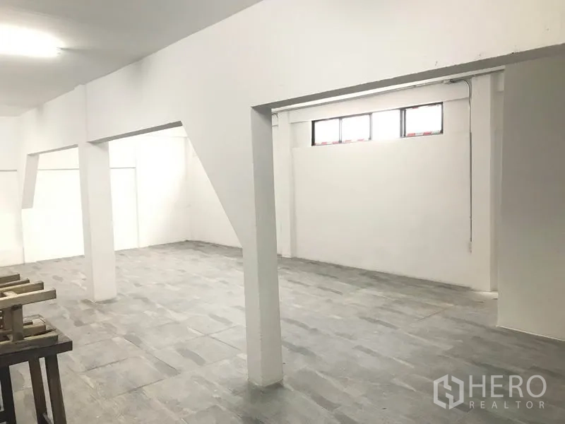 Office Space for rent in Watthana, Bangkok - Open-plan office interior with white walls, grey tile flooring, support columns and high windows.