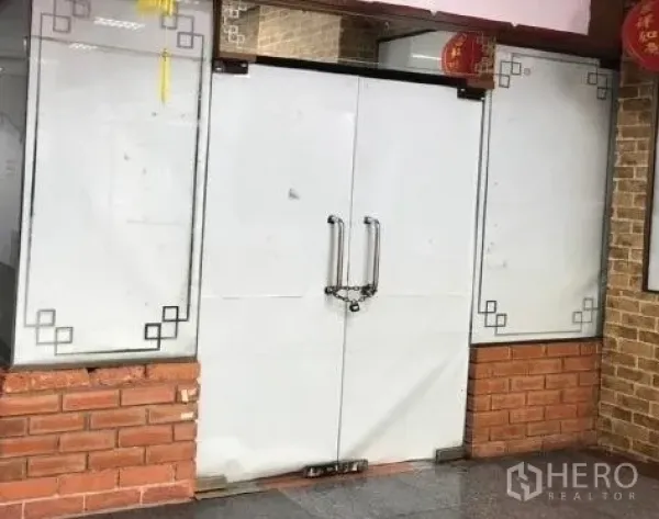 零售空间 出租 - 商铺门面，白色双开门、玻璃展示板与砖面立面，位于商业楼内