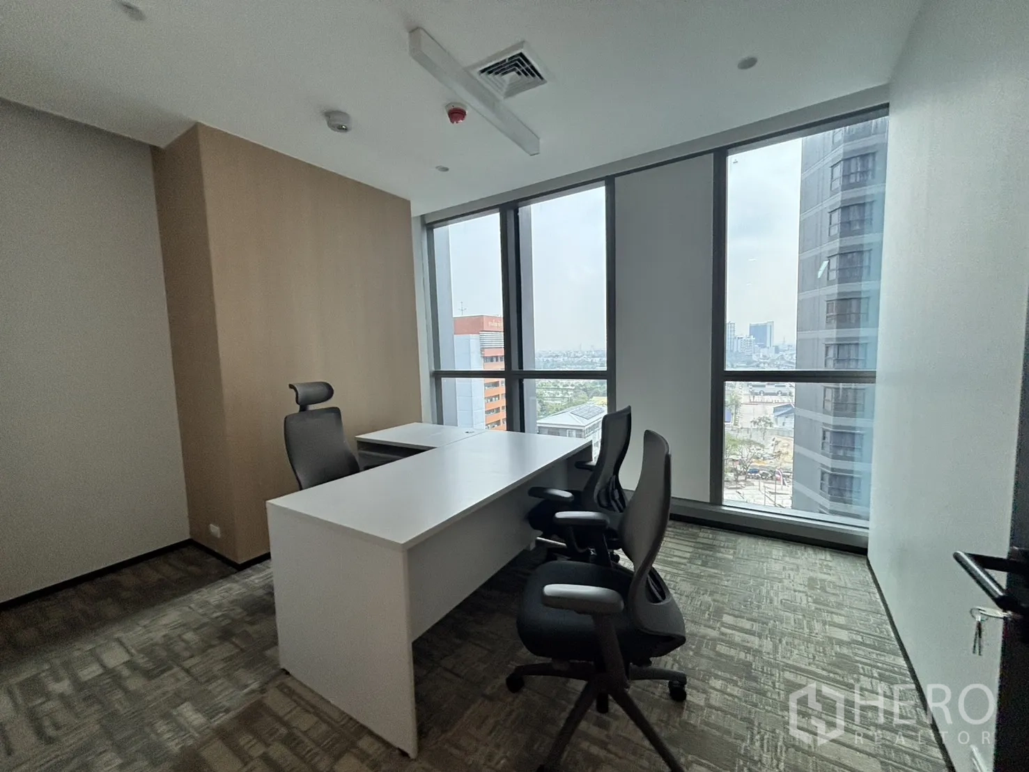 Office Space for rent in Huai Khwang, Bangkok - Private executive office with white desk and floor-to-ceiling windows showing city views.